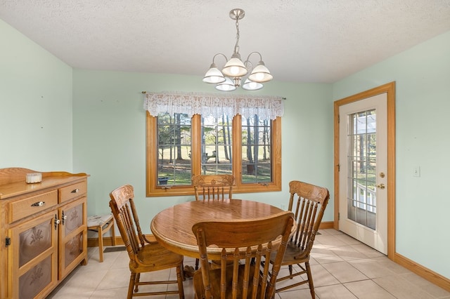 dining space with baseboards, a textured ceiling, a healthy amount of sunlight, and a notable chandelier