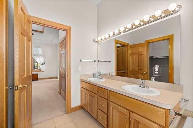 bathroom featuring double vanity, a sink, baseboards, and tile patterned flooring