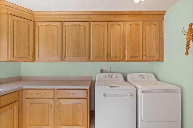 washroom with cabinet space, a textured ceiling, and washer and dryer