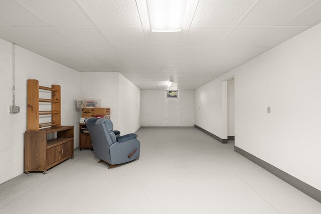 finished basement featuring baseboards, concrete block wall, and a drop ceiling