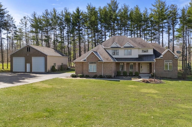 view of front of property with a detached garage, brick siding, an outbuilding, and a front lawn