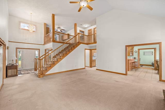living room featuring baseboards, carpet flooring, stairway, and ceiling fan with notable chandelier