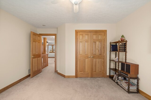 bedroom with light carpet, baseboards, a ceiling fan, and a textured ceiling