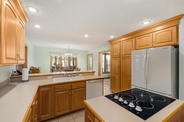 kitchen with light countertops, a peninsula, white appliances, a sink, and light tile patterned floors