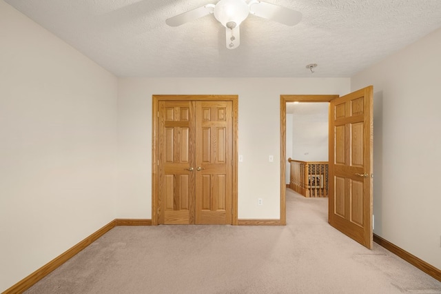 unfurnished bedroom with baseboards, light colored carpet, and a textured ceiling