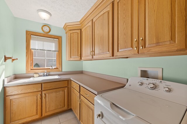 washroom with light tile patterned flooring, a sink, a textured ceiling, washer / clothes dryer, and cabinet space
