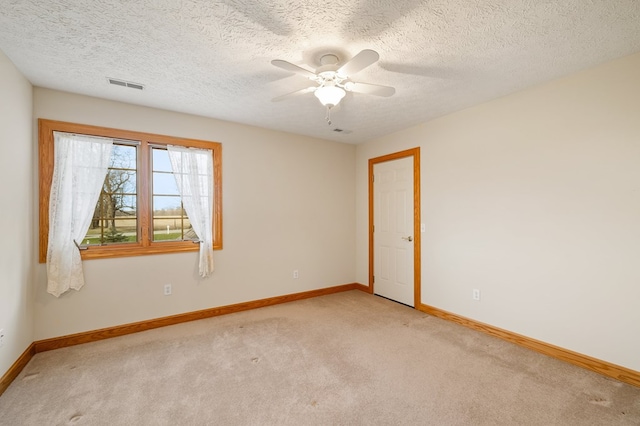 empty room featuring light carpet, a textured ceiling, baseboards, visible vents, and ceiling fan