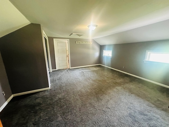 additional living space with dark carpet and vaulted ceiling