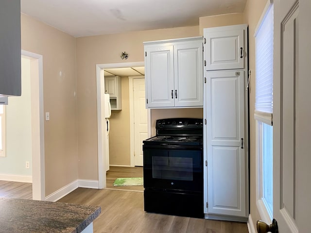 kitchen featuring black range with electric cooktop, light hardwood / wood-style floors, and white cabinetry