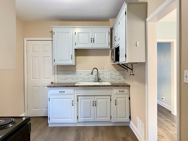 kitchen featuring sink, white cabinets, and dark stone counters