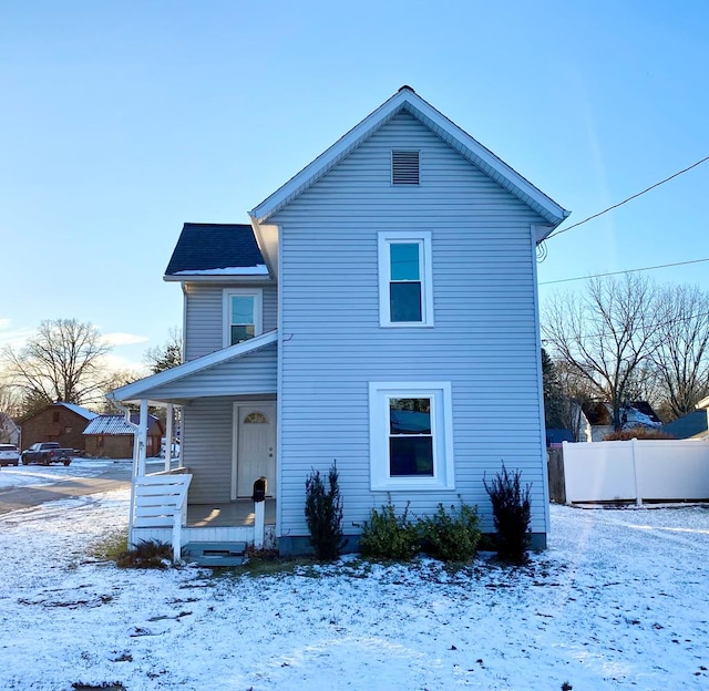 snow covered rear of property featuring covered porch