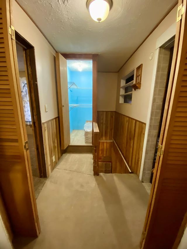 hall with wooden walls and a textured ceiling