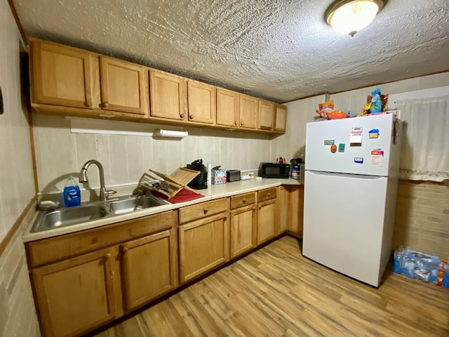 kitchen with sink, white fridge, and light wood-type flooring