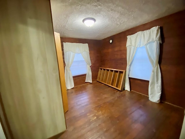 bonus room with wood-type flooring and a textured ceiling