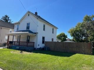 rear view of house with covered porch and a yard