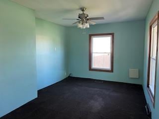 unfurnished room featuring ceiling fan and dark carpet