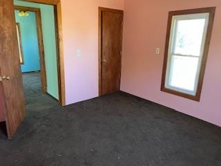 unfurnished bedroom with dark colored carpet