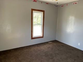 empty room with dark colored carpet, plenty of natural light, and ceiling fan