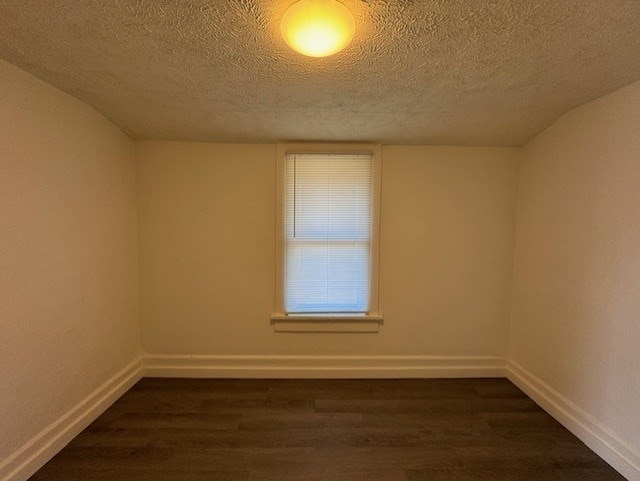 unfurnished room with dark wood finished floors, baseboards, and a textured ceiling