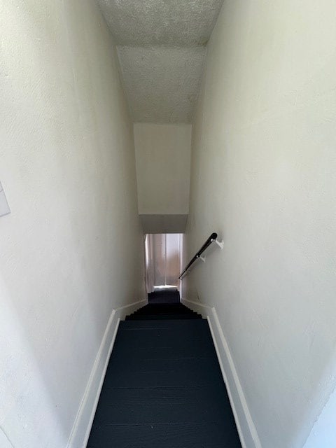 staircase with a textured ceiling and baseboards