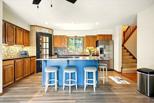 415 Lakeshore Rd, Ashland, OH 44805 - kitchen with stainless steel fridge with ice dispenser, a ceiling fan, light wood-style flooring, a breakfast bar, and decorative backsplash