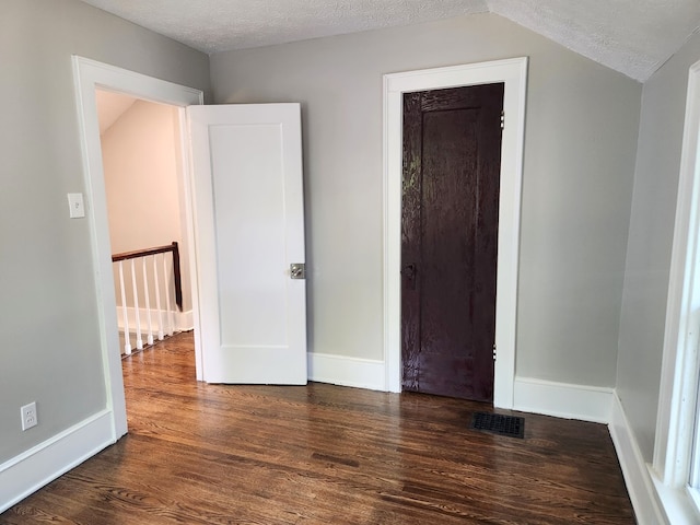 unfurnished bedroom featuring dark hardwood / wood-style flooring and a textured ceiling