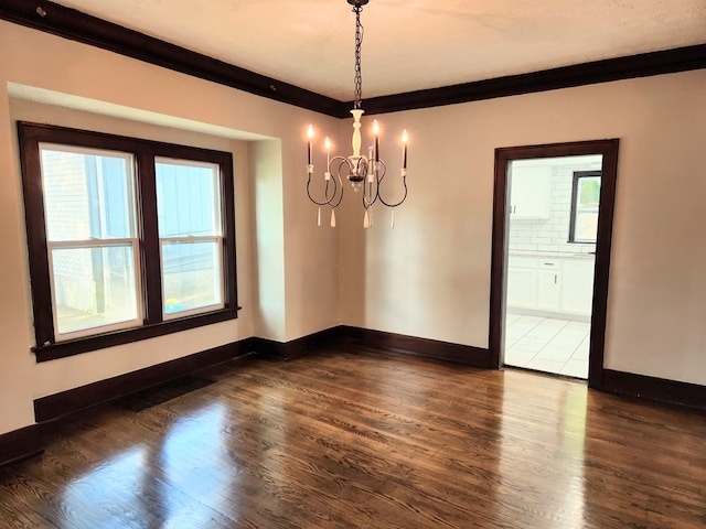 unfurnished room featuring dark hardwood / wood-style floors, ornamental molding, and a chandelier