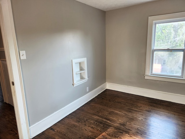 unfurnished room featuring dark hardwood / wood-style flooring and built in features