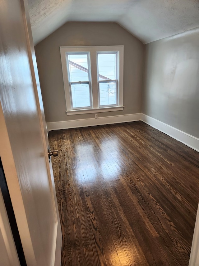 bonus room with vaulted ceiling, dark hardwood / wood-style flooring, and a textured ceiling