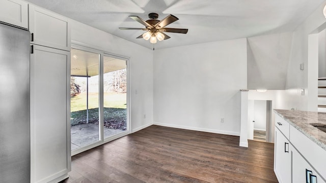 interior space with white cabinetry, dark hardwood / wood-style flooring, ceiling fan, and light stone counters