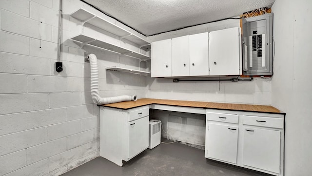 kitchen featuring white cabinetry, a textured ceiling, and electric panel