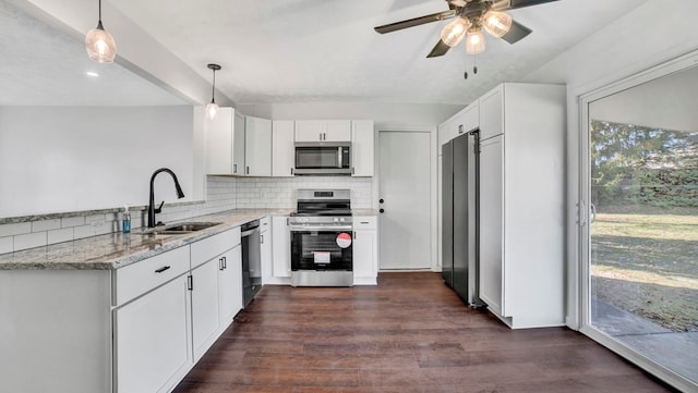 kitchen featuring light stone counters, stainless steel appliances, sink, decorative light fixtures, and white cabinetry