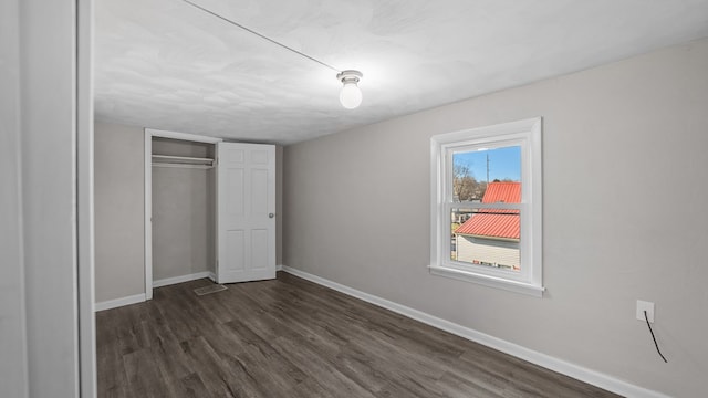 unfurnished bedroom with dark hardwood / wood-style floors and a closet