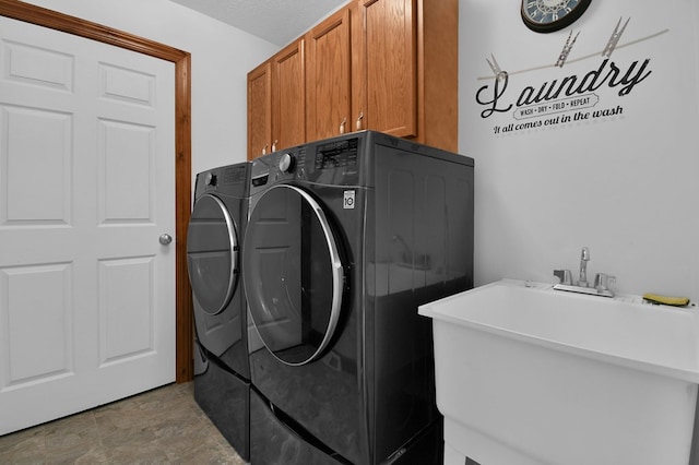 laundry room with washing machine and dryer, cabinet space, and a sink