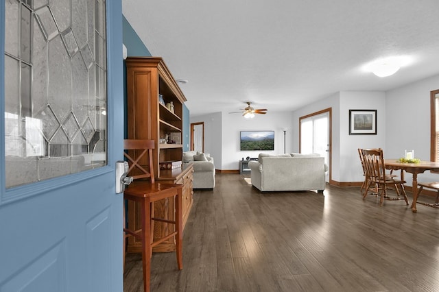 living area featuring dark wood finished floors, a ceiling fan, and baseboards