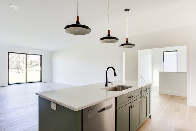 kitchen featuring stainless steel dishwasher, sink, decorative light fixtures, light hardwood / wood-style floors, and an island with sink