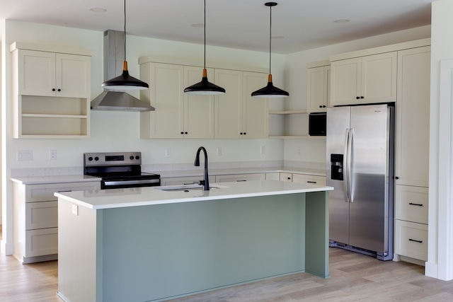 kitchen with a center island with sink, wall chimney range hood, sink, light hardwood / wood-style flooring, and appliances with stainless steel finishes