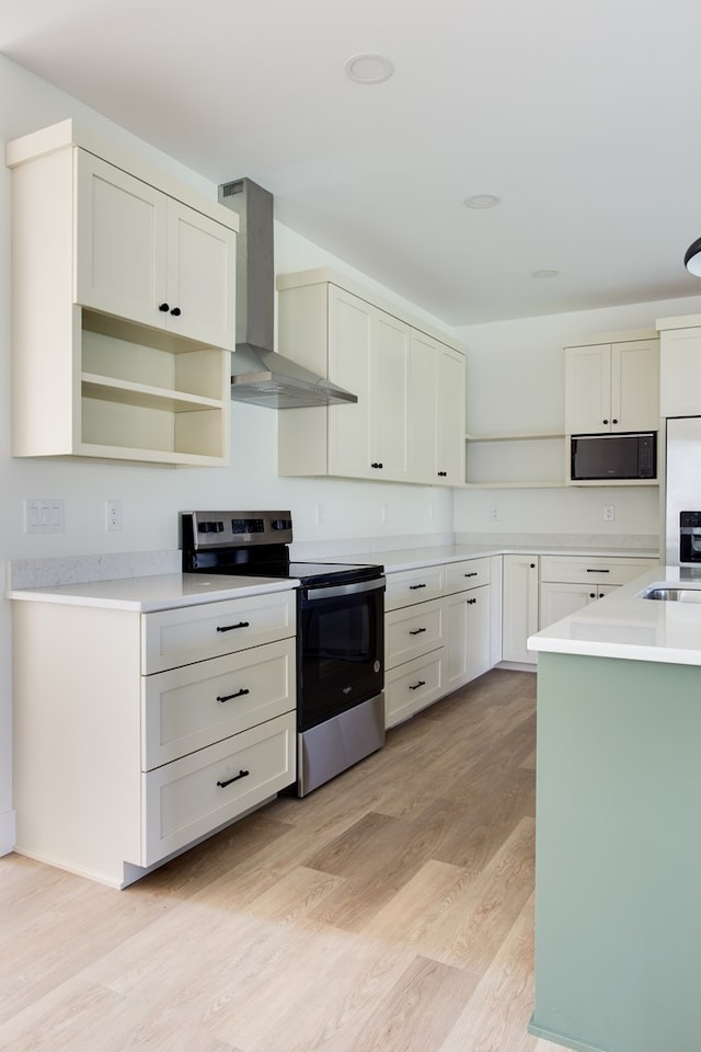 kitchen featuring white cabinets, light wood-type flooring, wall chimney range hood, and stainless steel appliances