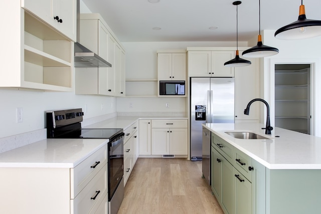 kitchen featuring pendant lighting, sink, green cabinetry, built in appliances, and wall chimney exhaust hood