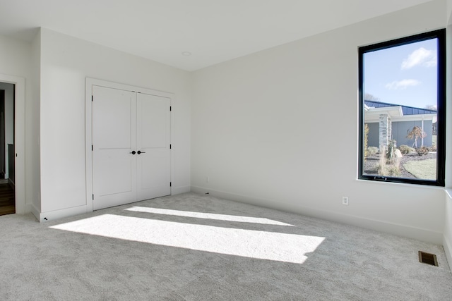 unfurnished bedroom featuring light colored carpet and a closet