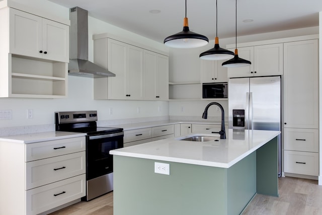 kitchen featuring a center island with sink, sink, wall chimney exhaust hood, decorative light fixtures, and stainless steel appliances