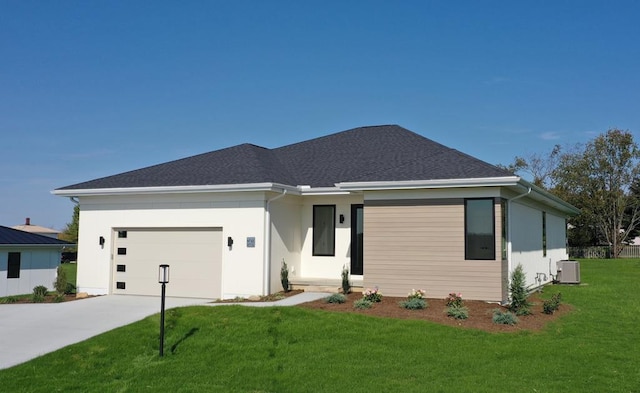 view of front of home featuring central AC unit, a front yard, and a garage