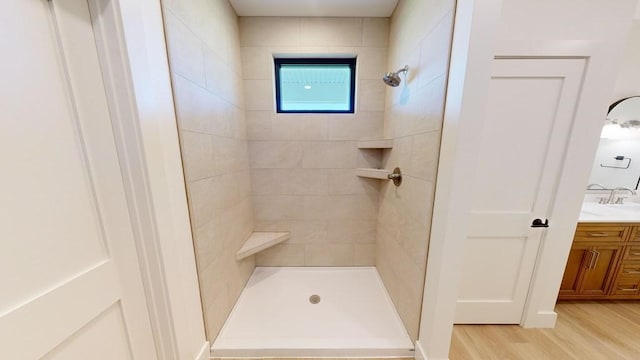 bathroom featuring vanity, wood-type flooring, and tiled shower