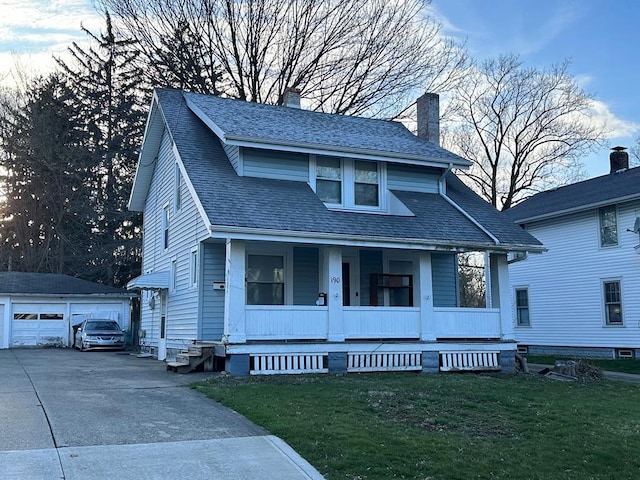 view of front facade with a porch, an outbuilding, a front yard, and a garage