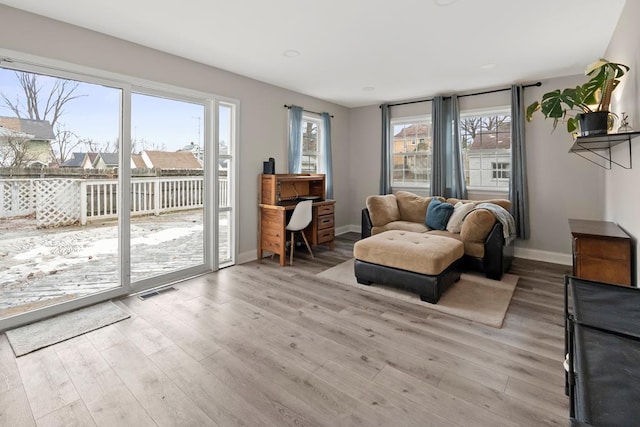 living area featuring light wood-type flooring, visible vents, and baseboards