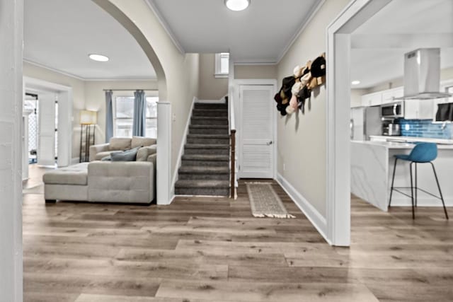 entryway featuring stairway, light wood-style flooring, and ornamental molding