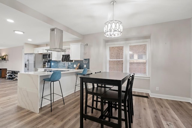 dining room featuring light wood finished floors, baseboards, a notable chandelier, and recessed lighting