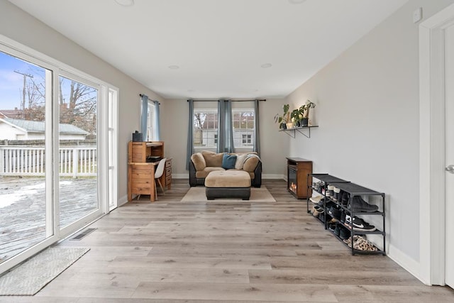 living area featuring visible vents, light wood-style flooring, and baseboards