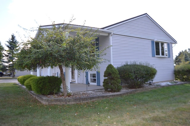 view of property exterior with a yard and a patio