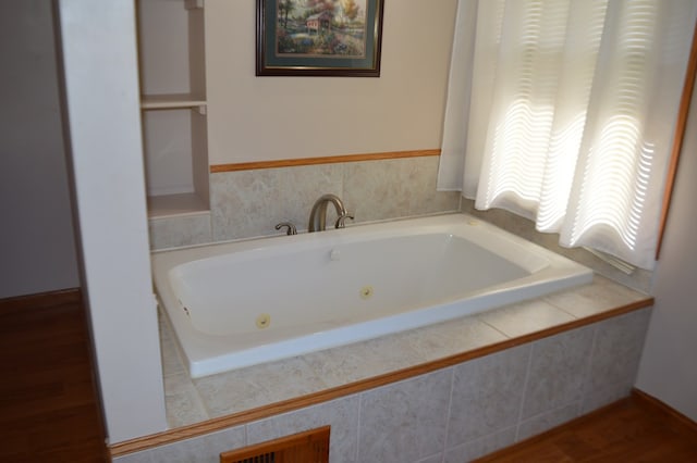 bathroom with hardwood / wood-style floors and tiled tub